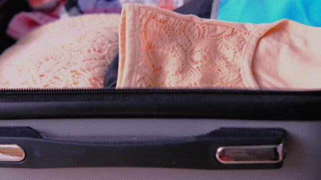 сclose-up of bright women's phone, folded clothes in open silvery suitcase, woman packing things, documents, concept collecting wardrobe for summer vacation, business trip, go on long-awaited voyage
