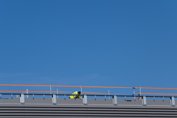 Worker on flat roof with orange temporary railing