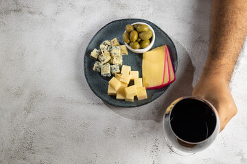 Plate of different cheeses with a glass of wine.