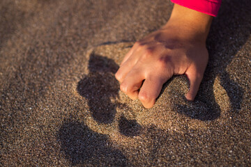 Hand of unrecognizable brunette Latina woman grabbing sand from the dunes of a South American beach.