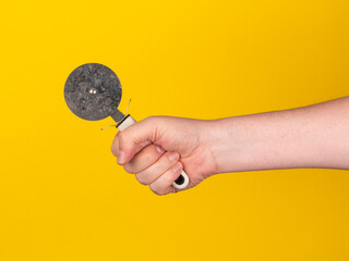 Pizza cutter in front of yellow background. Male hand, no face, copy space.
