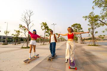 Group of Young Asian man and woman friends skating on longboard skate at public park on summer...