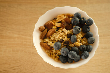 close-up healthy food white cup on light table, oatmeal, blueberries, nuts, almonds, peanuts , raisins, dried fruits, raw food diet, vegetarian food