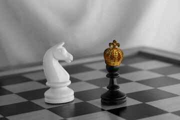 gold, bronze crown on black pawn, duel queen figures, horse on chessboard blackboard, concept supreme power, victory, symbol superiority, supreme dignity, level in hierarchy, leadership in business