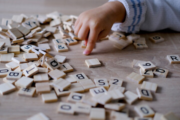 hands close-up, small child 3 years old plays wooden alphabet blocks, makes up words from letters, dyslexia awareness, learning difficulties, human brain development, happy childhood, selective focus - obrazy, fototapety, plakaty