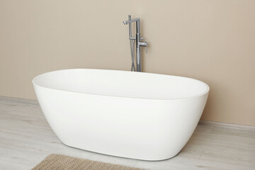 Beautiful white tub near beige wall in bathroom. Interior design