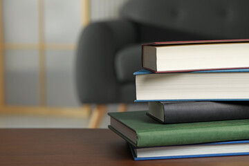 Stack of hardcover books on wooden table indoors, space for text