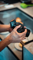 Mãos de homem de tez clara gravando com câmera dslr preta em restaurante 