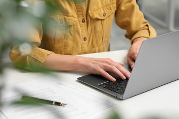 Woman working on laptop at white desk in office, closeup