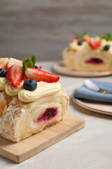 Tasty meringue roll with jam, cream, strawberry, blueberry and mint on light grey marble table, closeup