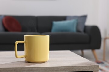 Fototapeta na wymiar Yellow mug on wooden table indoors, space for text