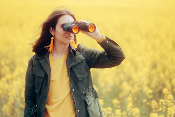Woman Using Binocular Checking Nature from a Distance. Happy adventurous girl using a pair of...