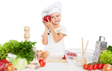 little cute chef holding wooden spoon with different pair of gloves looking at camera and smiling on gray background