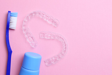 Transparent plastic dental aligners and care products on a colored background