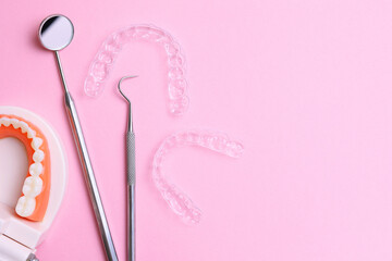 Obraz na płótnie Canvas Transparent plastic aligners and dentist's tools on a colored background