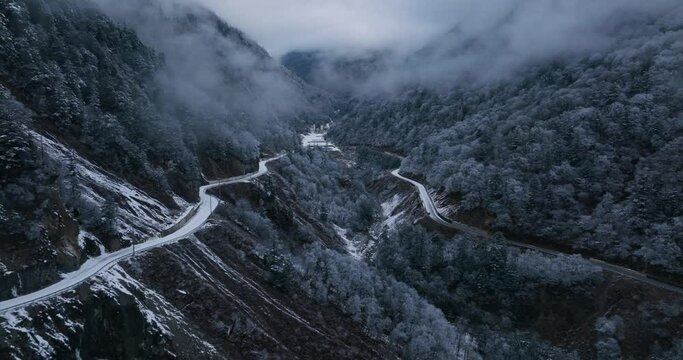 Close-up of highways go through mountains and hills as one falls another rise and snow is melting. Aerial picture of a heaven of serenity in countryside of China in morning.