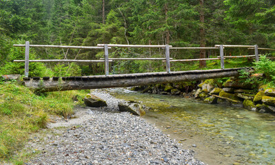 old wooden bridge over a small river in the forest
