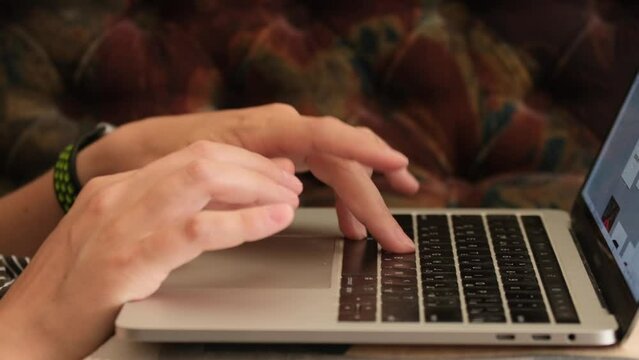 Close up of web designer's hands working on laptop at home