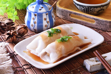 Steamed rice rolls with fresh prawn filling served in a dish  on wooden table 