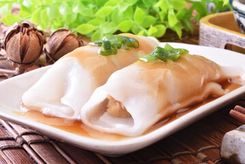 Steamed rice rolls with fresh prawn filling served in a dish  on wooden table 