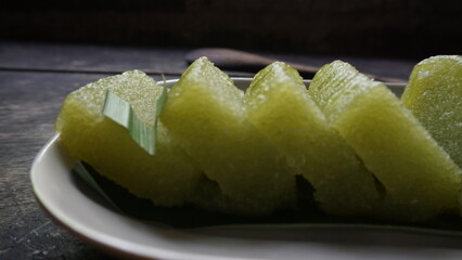 Lemet Singkong or Utri or Ketimus or ongol-ongol is a traditional cake that uses processed grated cassava inside which is mixed brown sugar and steamed,  Served in white plate and wooden background.
