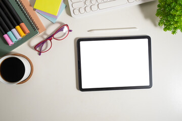 Flat lay, top view of digital tablet with empty screen, glasses and stationery on white table.
