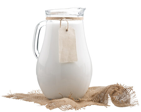 Fresh organic milk in glass and jug on rustic wooden table on nature background.