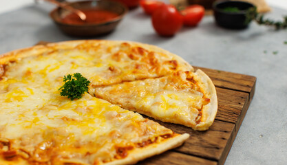 Closeup top view shot of delicious tasty juicy sliced piece of double cheese traditional Italian crust thin crispy pizza out of oven placed on wooden cutting board ready to serve on table for dinner
