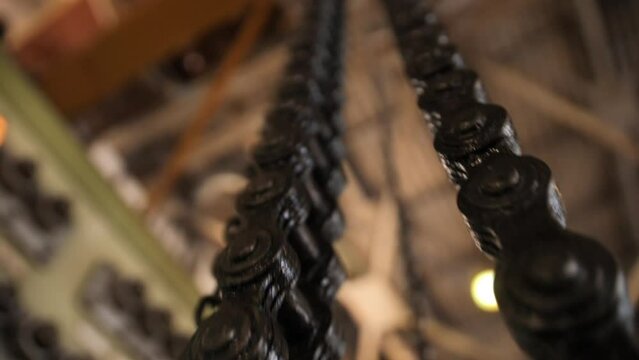 Huge greasy roller chain in motion. A crawler chain covered with machine oil. Conveyor belt in work.