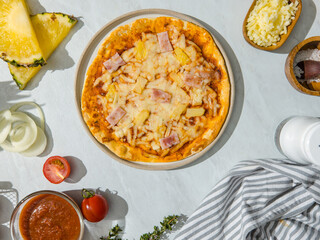Top view shot of triangle shape piece of delicious tasty Hawaiian traditional Italian crust thin crispy ham and pineapple pizza stretching cheese up from table.