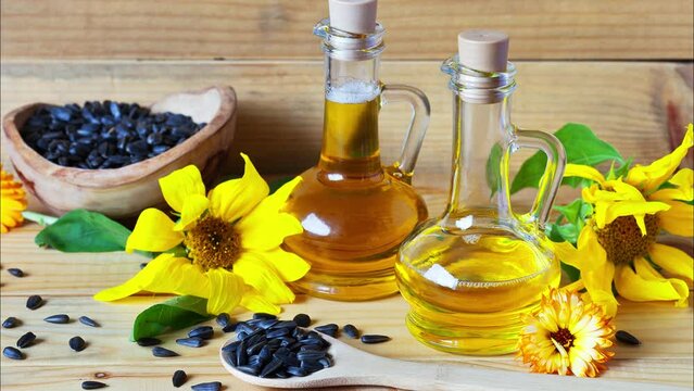 Rustic still life with sunflower oil and flowers of sunflower and calendula on a wooden background. In two glass jugs, refined and unrefined oil. Natural organic healthy food