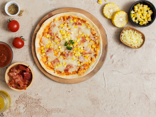 Top view closeup shot of delicious tasty juicy thin crispy cheesy corn and ham Italian pizza placed on wooden board on party table around with other ingredients, sauce, olive oil, bacon and tomatoes