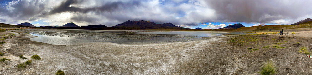 Panorama of shallow salt lake in Bolivia, with storm clouds on the horizon.