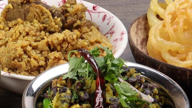 Bengali Iftar Ramadan breakfast spread ripe dates peep fried spicy piaju onion fitter eggplant tanpura potato chop haleem jilapi khichuri rice chana sola curry on rustic wooden table zoom out pan