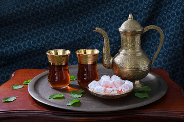 Classic celebratory ornate Turkish teapot two glasses traditional Turkish delights tray wooden table soft lighting