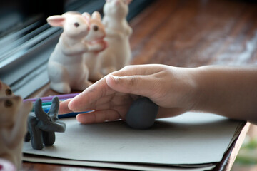 An autistic boy molding different shapes of colored plasticine prepared by parents at home in order...