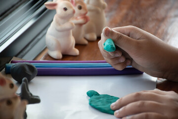 An autistic boy molding different shapes of colored plasticine prepared by parents at home in order to develop various aspects in their son which has slower brain development than normal children.