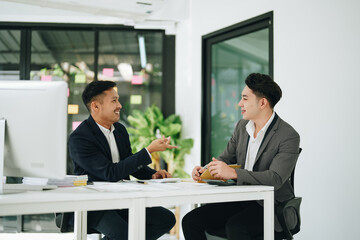 Two business men meeting to talking or discuss marketing work in workplace using paperwork, calculator, computer to work.