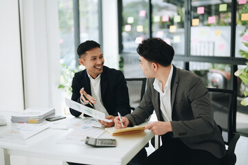 Two business men meeting to talking or discuss marketing work in workplace using paperwork, calculator, computer to work.