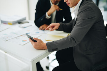 Two business men meeting to talking or discuss marketing work in workplace using paperwork, calculator, computer to work.