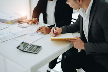 Two business men meeting to talking or discuss marketing work in workplace using paperwork, calculator, computer to work.