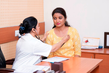 Indian female doctor checking with stethoscope to woman at clinic.