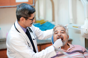 Dentist checking senior patient teeth at clinic