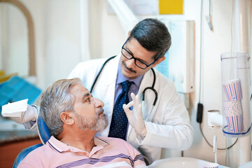 Dentist checking senior patient teeth at clinic