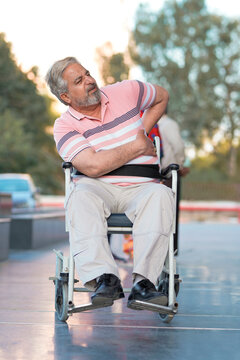 Indian old man sitting on wheel chair and moaning pain.