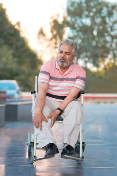 Indian old man sitting on wheel chair and moaning pain.