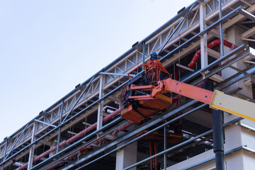 MEP Construction Workers are working insatallation Fire Protection Steel pipe at Roof structure by use boomlift machine for work at hight