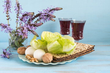 Traditional meal (matzah, eggs, salad leaves, walnuts) for Jewish holiday Pesach (Passover) on blue wooden background.