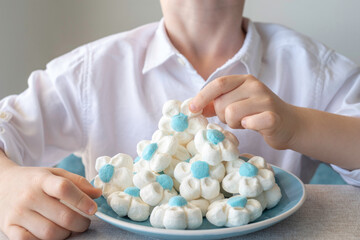 White and blue marshmallows in the form of flowers and hands of a child.