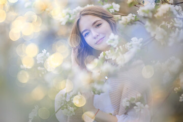 spring portrait of an adult happy woman in a blooming garden, sun rays and glare, april flowers girl